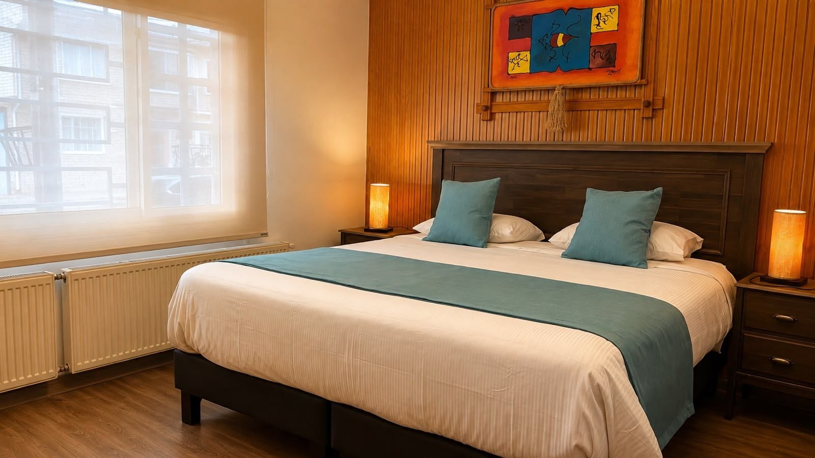A hotel room with a bed, bedside lamps, a window, and a wooden headboard.