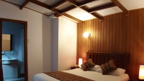Een slaapkamer met een houten hoofdbord, een groot bed met witte beddengoed, twee bedlampen en een nachtkastje.