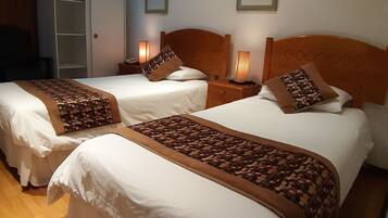 Habitación de hotel con dos camas, cabeceros de madera y lámparas de noche.