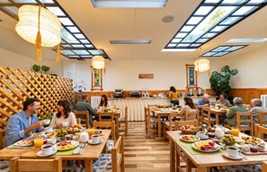 Un comedor con varias mesas, sillas y una variedad de alimentos para el desayuno.
