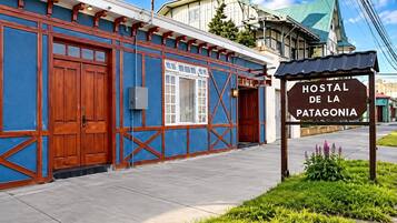 Rakennuksessa on kyltti, jossa lukee ”HOSTAL DE LA PATAGONIA”, ja sen julkisivu on sininen, ja siinä on puuelementtejä.