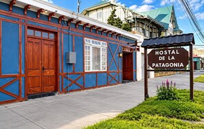Un edificio con un letrero que dice 'HOSTAL DE LA PATAGONIA' y fachada azul con detalles de madera.