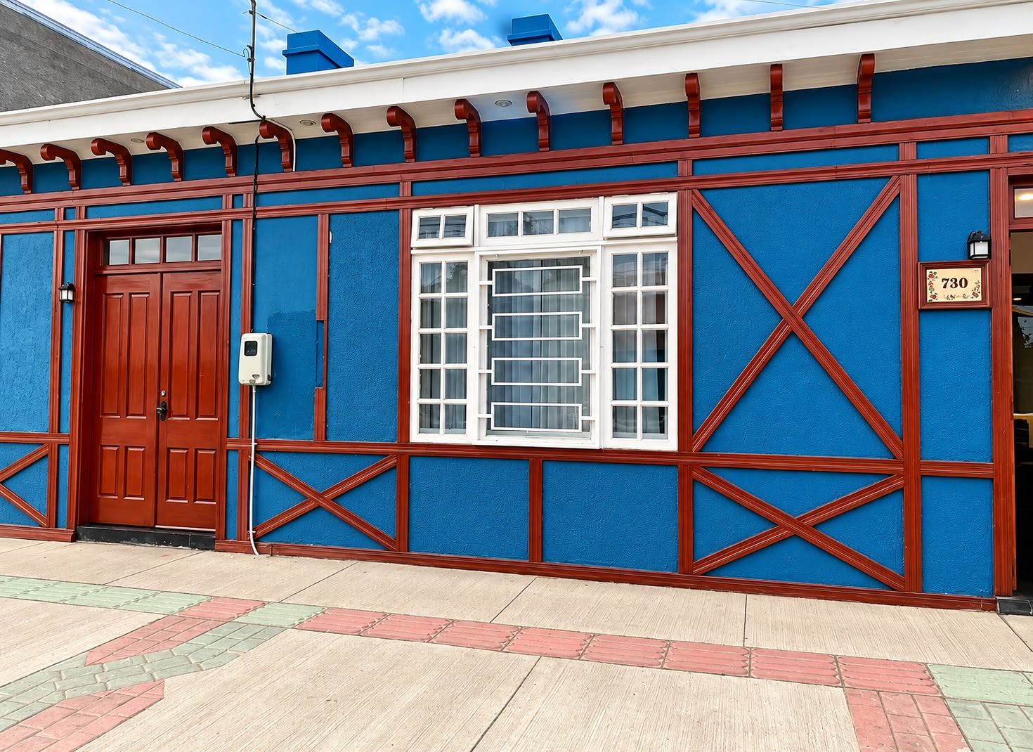 A building with a blue facade, a red door, and a window with white frames.