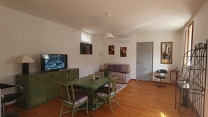 Un espacio habitable compacto con comedor, televisión, sofá y escalera.