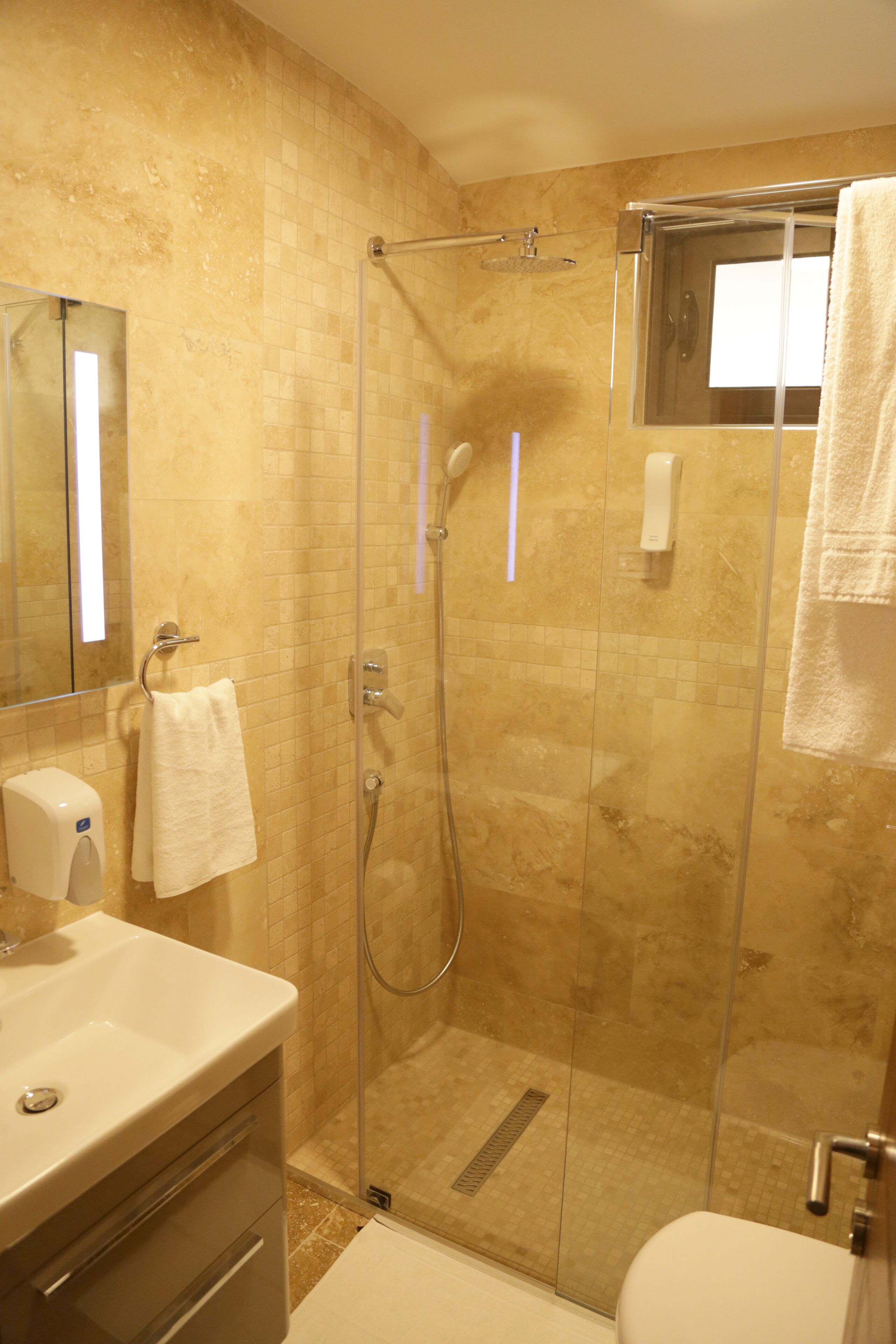 A modern bathroom with a glass-enclosed shower, a sink, and a toilet.