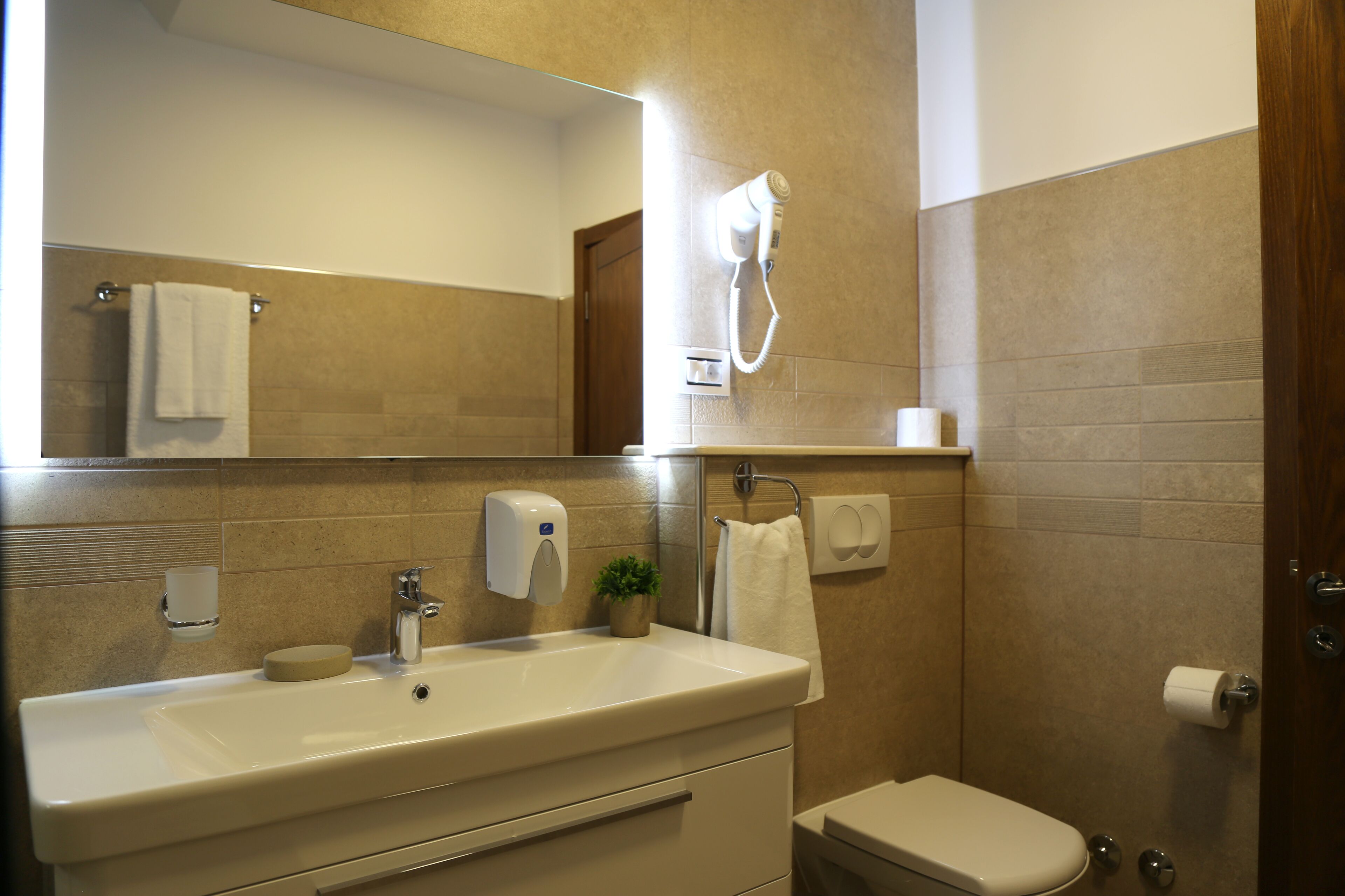 Baño con lavamanos, espejo, secador de pelo, toallero y retrete.