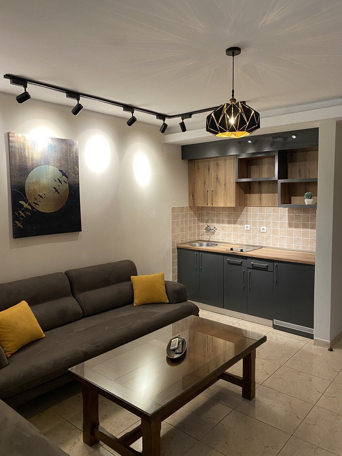 A modern kitchen with dark cabinets, a wooden countertop, and a hanging light fixture.