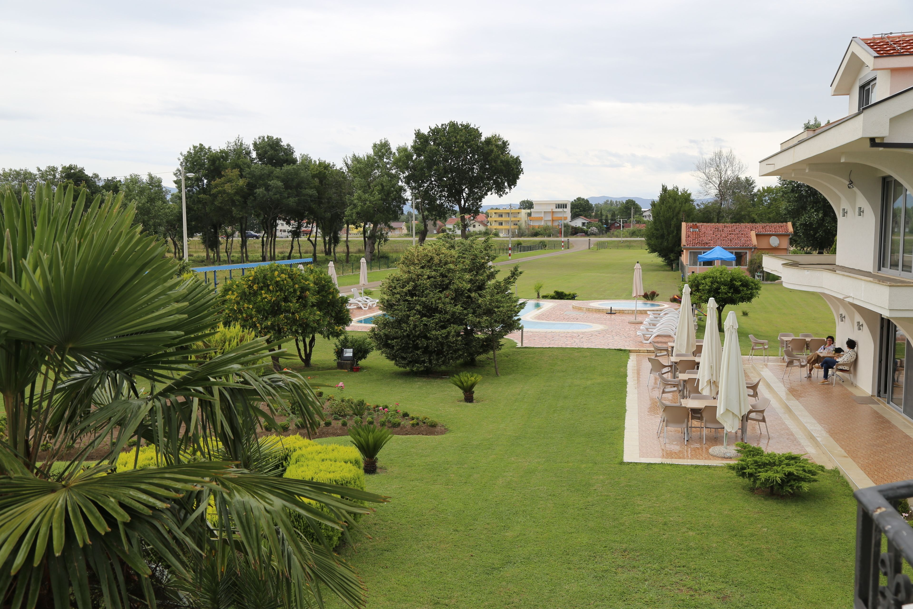 A hotel courtyard with a pool, outdoor seating, and a view of the surrounding area.