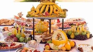 Una mesa de buffet con una variedad de alimentos, como frutas, quesos y carnes.