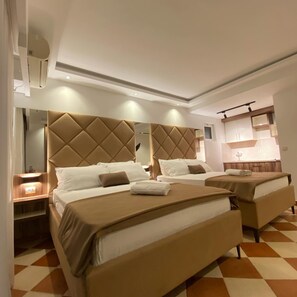 Une chambre d’hôtel avec deux lits, un grand miroir et une kitchenette.