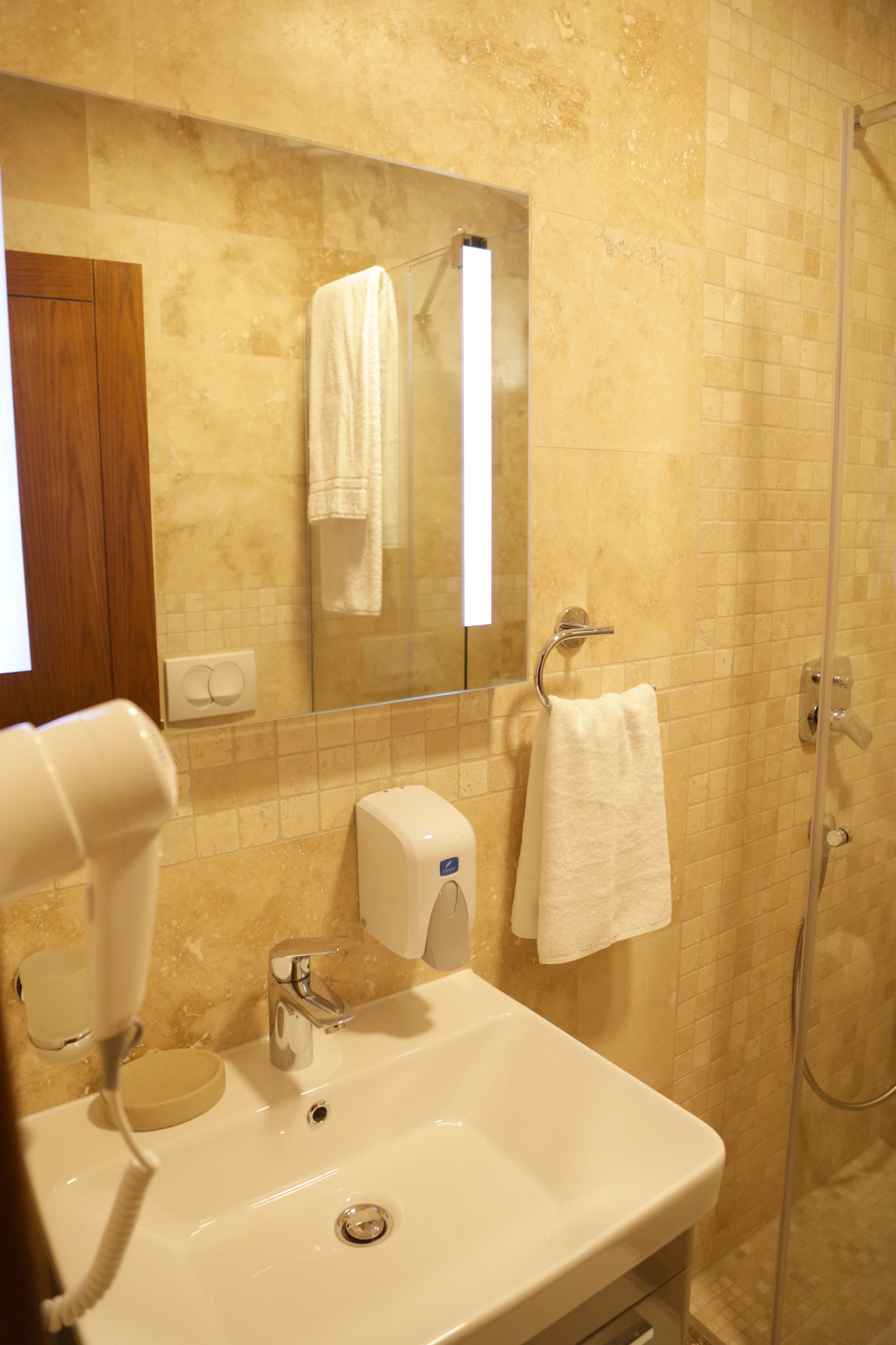 A bathroom with a sink, a mirror, a towel rack, and a shower.