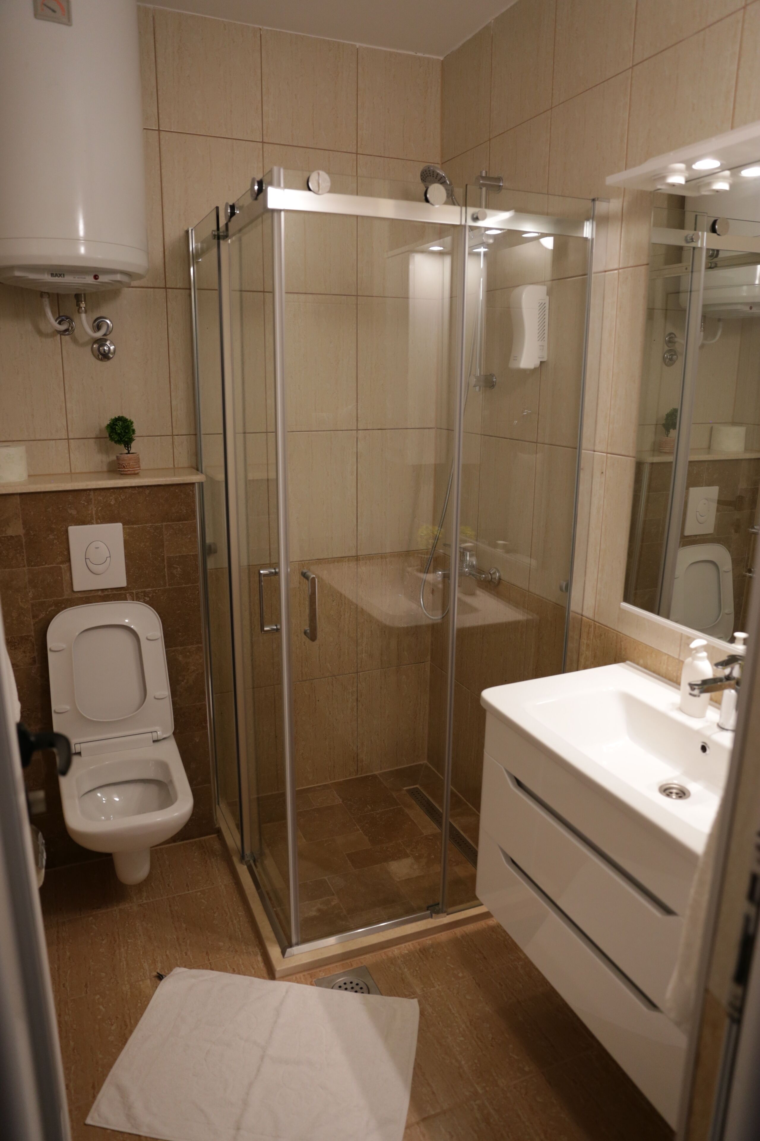 A bathroom with a glass-enclosed shower, a toilet, and a sink with a mirror.