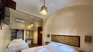 Une chambre d’hôtel avec deux lits, un grand miroir, une tête de lit en bois et un luminaire suspendu.