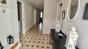 A hallway with a tiled floor, white walls, and a black console table with decorative items.