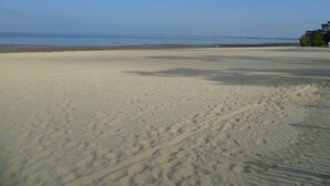Een zandstrand met voetafdrukken die naar het water leiden.