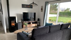 Un salon moderne avec un grand canapé gris, une table basse en bois, un téléviseur à écran plat et une cheminée noire.