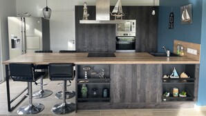 Une cuisine moderne dotée d’un îlot central, de tabourets de bar, d’un four encastré et d’un four à micro-ondes.