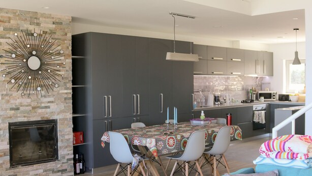 A modern living room with a blue sofa, a fireplace, and a dining area with a table and chairs. - Spectacular ocean views - 5 min walk to beach (Ericeira)