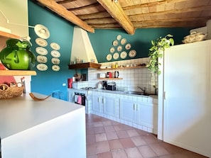 A kitchen with white cabinets, a green wall, and a tiled backsplash. - Luxury apartment in Tuscan villa with pool: your own window to iconic Siena! (Siena)