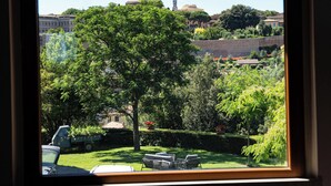 Ein Fenster mit Blick auf einen Baum, ein Auto und Gebäude in der Ferne.