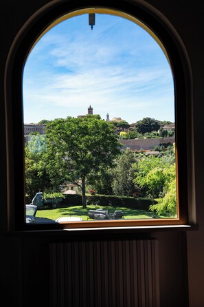A window with a view of a tree, a car, and buildings in the distance. - Luxury apartment in Tuscan villa with pool: your own window to iconic Siena! (Siena)