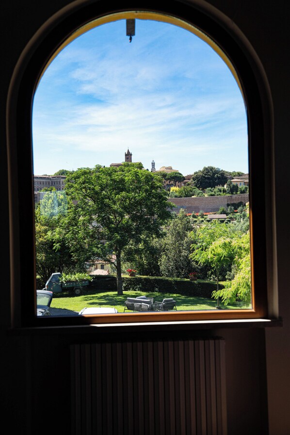 A window with a view of a tree, a car, and buildings in the distance. - Luxury apartment in Tuscan villa with pool: your own window to iconic Siena! (Siena)