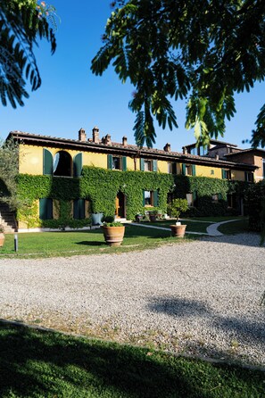 A building with a yellow facade, green shutters, and ivy-covered walls. - Luxury apartment in Tuscan villa with pool: your own window to iconic Siena! (Siena)