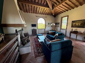A spacious living room with a high wooden ceiling, a fireplace, a sofa set, and a dining area. - Luxury apartment in Tuscan villa with pool: your own window to iconic Siena! (Siena)
