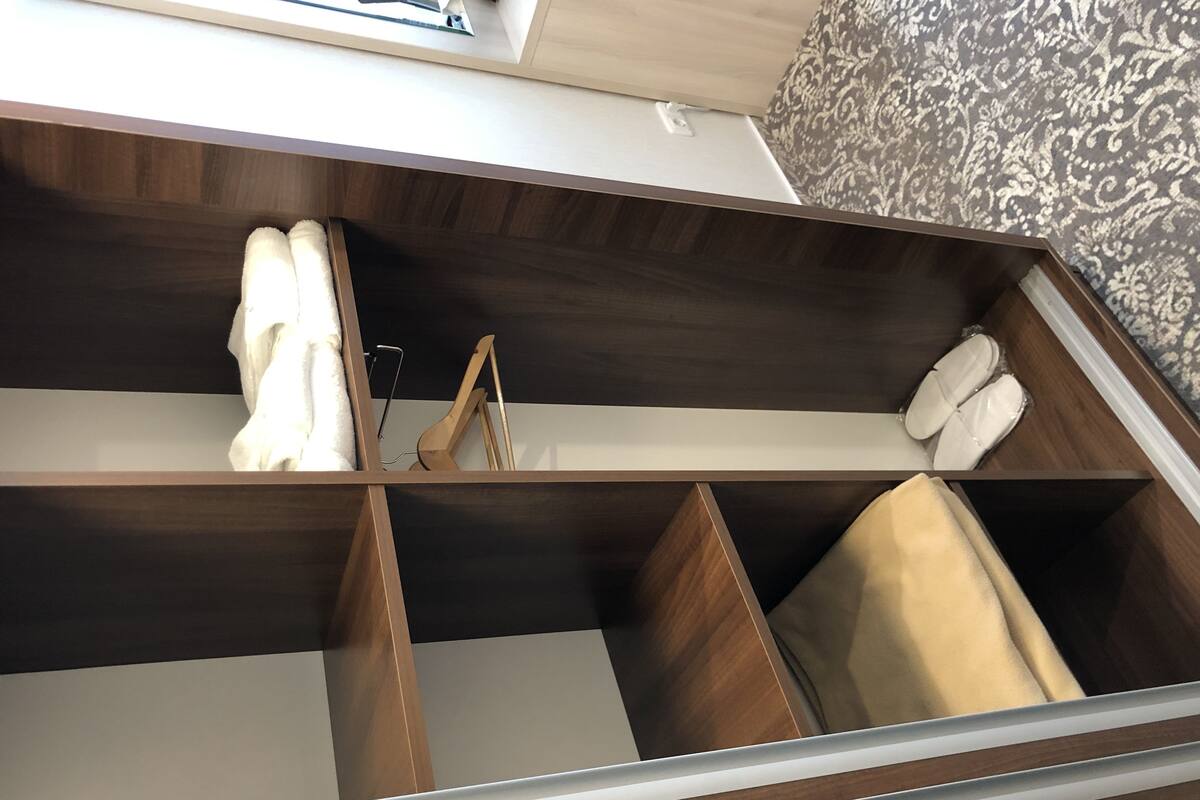 Un placard bien organisé, doté de plusieurs compartiments, notamment un espace pour suspendre les vêtements et des tiroirs.
