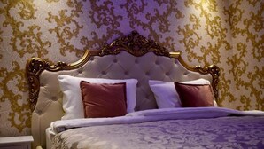 Een slaapkamer met een gestoffeerd hoofdeinde, twee kussens en een bedsprei met een patroon.