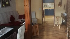A cozy living room with a wooden ceiling, a dining area with a table set for two, and a kitchen visible through an open doorway. - Glori * s apartment (Bad Sooden-Allendorf)