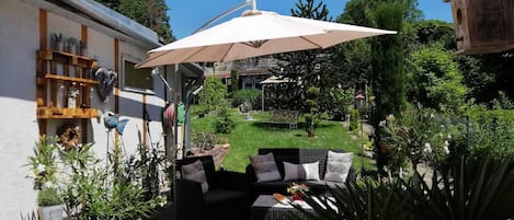Un patio con mobiliario exterior, una pérgola y un jardín.