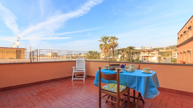 Una terraza con mesa y sillas, vista a la ciudad y una palmera.