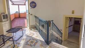 Una habitación con balcón, una pequeña mesa, una silla y un plato decorativo en la pared.