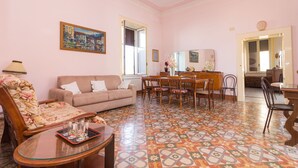 Una sala de estar con sofá, sillas, una mesa de comedor y un suelo estampado y colorido.