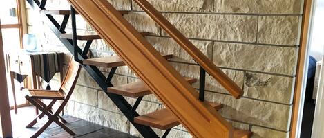 A wooden staircase with a stone wall background.
