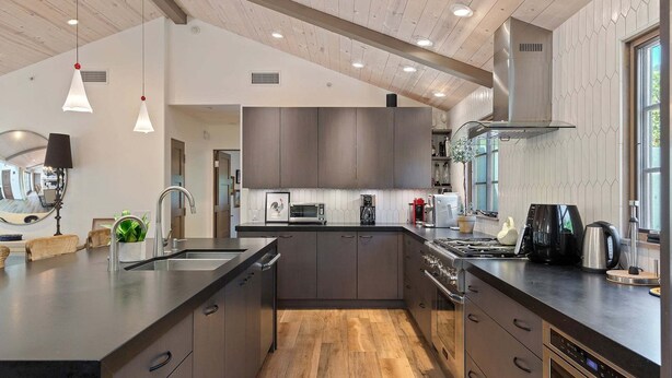 A modern kitchen with a central island, stainless steel appliances, and a large window.