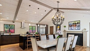 A spacious kitchen with a central island, pendant lighting, and a fireplace.