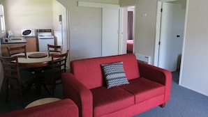 Un espacio habitable compacto con comedor, kitchenette y un sofá rojo.