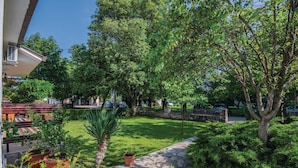 Een verzorgde tuin met een pad van stenen, diverse potplanten en een bankje.