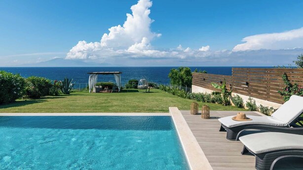 Un espace aménagé au bord de la piscine, avec vue sur l’océan, agrémenté d’une pergola et de chaises longues.