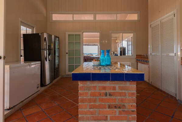 A kitchen with a brick island, a refrigerator, and a window overlooking a patio.