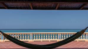 Una hamaca en una terraza con baldosas, con vista a un mar azul y despejado.