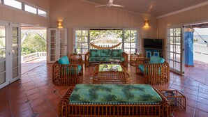 Un salón amplio con una hamaca, muebles de mimbre y un televisor.