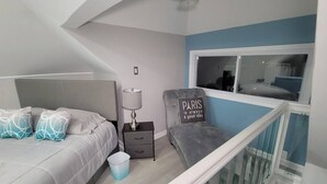 A bedroom with a bed, bedside table, lamp, and a chair with a cushion. - Romantic Escape to The Luxury Loft (Detroit)