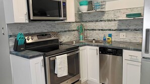 A modern kitchen with stainless steel appliances, white cabinets, and a marble backsplash. - Romantic Escape to The Luxury Loft (Detroit)