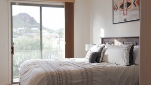 A bedroom with a large bed, a view through a sliding glass door, and a mountain landscape. - Two Mountain Views in Gold Canyon (Gold Canyon)