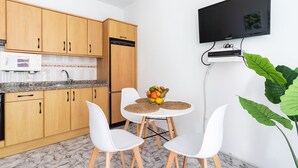 Une cuisine compacte avec des meubles en bois, un four à micro-ondes et un panier de fruits posé sur le plan de travail.