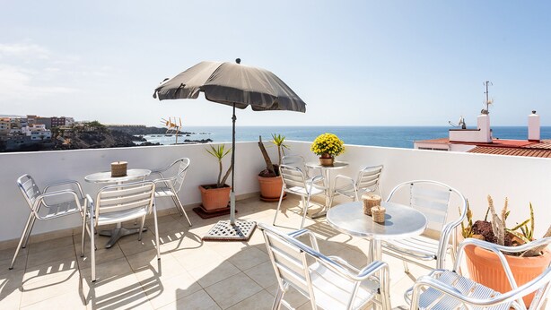 Une terrasse avec des sièges, une table et un pot de fleurs.