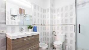 Une salle de bain moderne avec un meuble-lavabo blanc, une douche en verre et des toilettes.